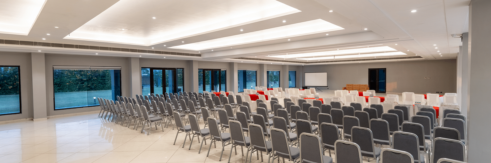 Spacious banquet hall at DLS Forest Vines Resort, with chairs neatly arranged and bright lighting illuminating the space.